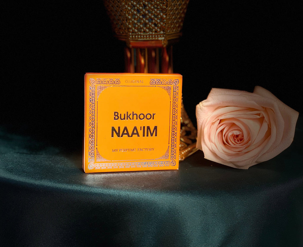 box of bakhoor in front of gold Bakhoor burner and light pink rose