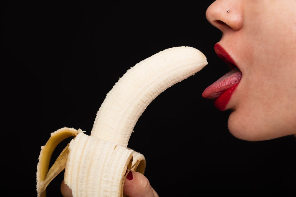 a woman is eating a banana in a sensual  manner